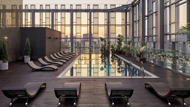 A rooftop pool area with lounge chairs, potted plants, and a view of the city skyline. - Novotel Ambassador Seoul Dongdaemun Hotels & Residences (Seoul)