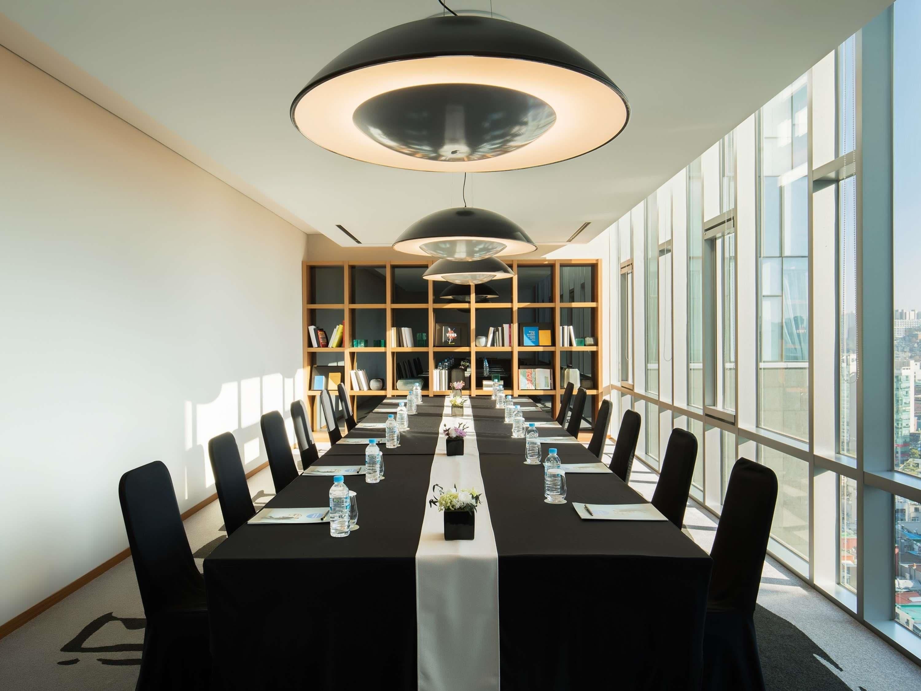 A conference room with a long table, chairs, water bottles, and a bookshelf.