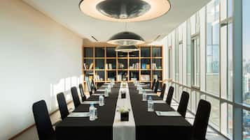 A conference room with a long table, chairs, water bottles, and a bookshelf.