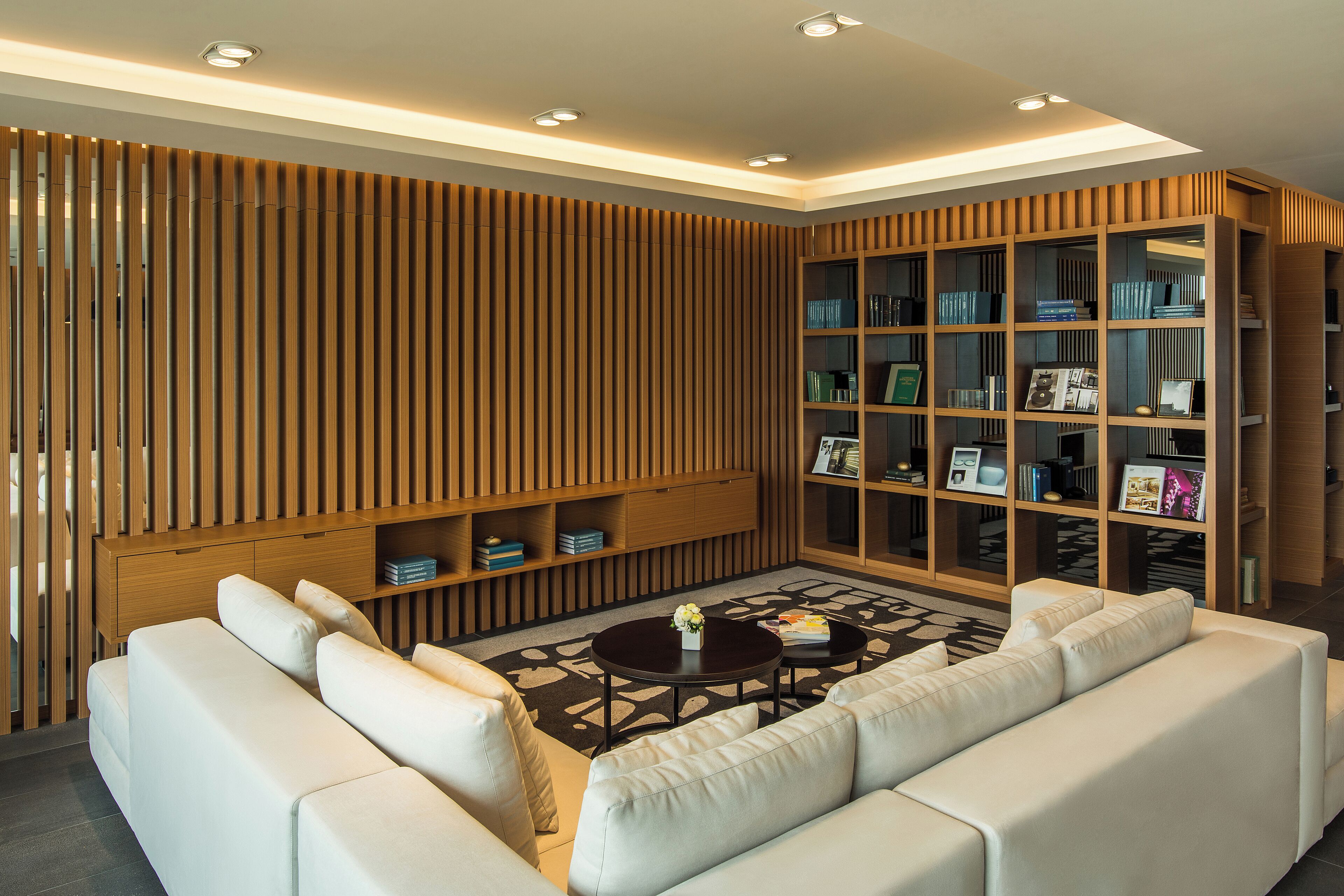 A modern living room with a sectional sofa, a coffee table, and a built-in bookshelf.