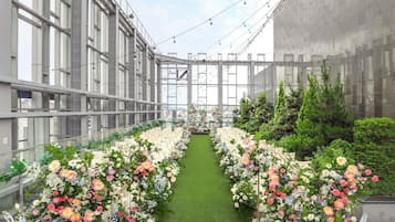 A rooftop garden with a central pathway, surrounded by lush greenery and flowering plants.