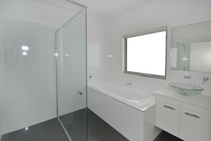 A modern bathroom with a glass shower enclosure, a white vanity with a glass bowl sink, and a large mirror above the sink. - 4/84 The Anchorage, (Port Macquarie)