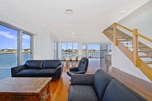 A spacious living area with a view of the water, a wooden staircase, and modern furniture. - 4/84 The Anchorage, (Port Macquarie)