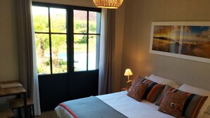 A hotel room with a bed, a desk, a lamp, and a window with curtains.