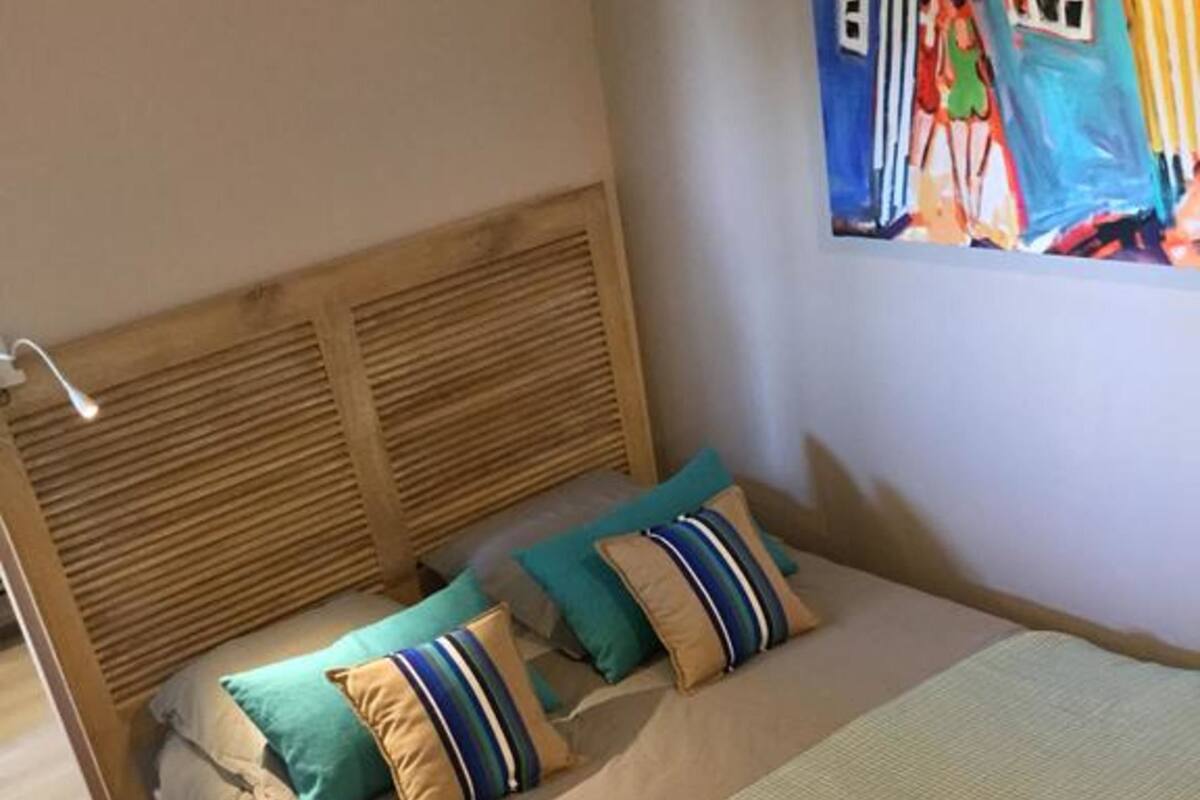 Ein Bett mit Holz-Kopfteil, mehreren Kissen und einer Decke.