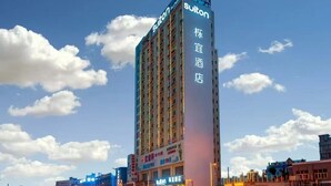 Un grand immeuble d’hôtel avec des panneaux indiquant « Suiton » et « Sutton Hotel ».