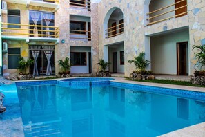 A modern building with a pool, stone facade, and multiple balconies. - Axkan Arte Hotel Tuxtla (Tuxtla Gutierrez)