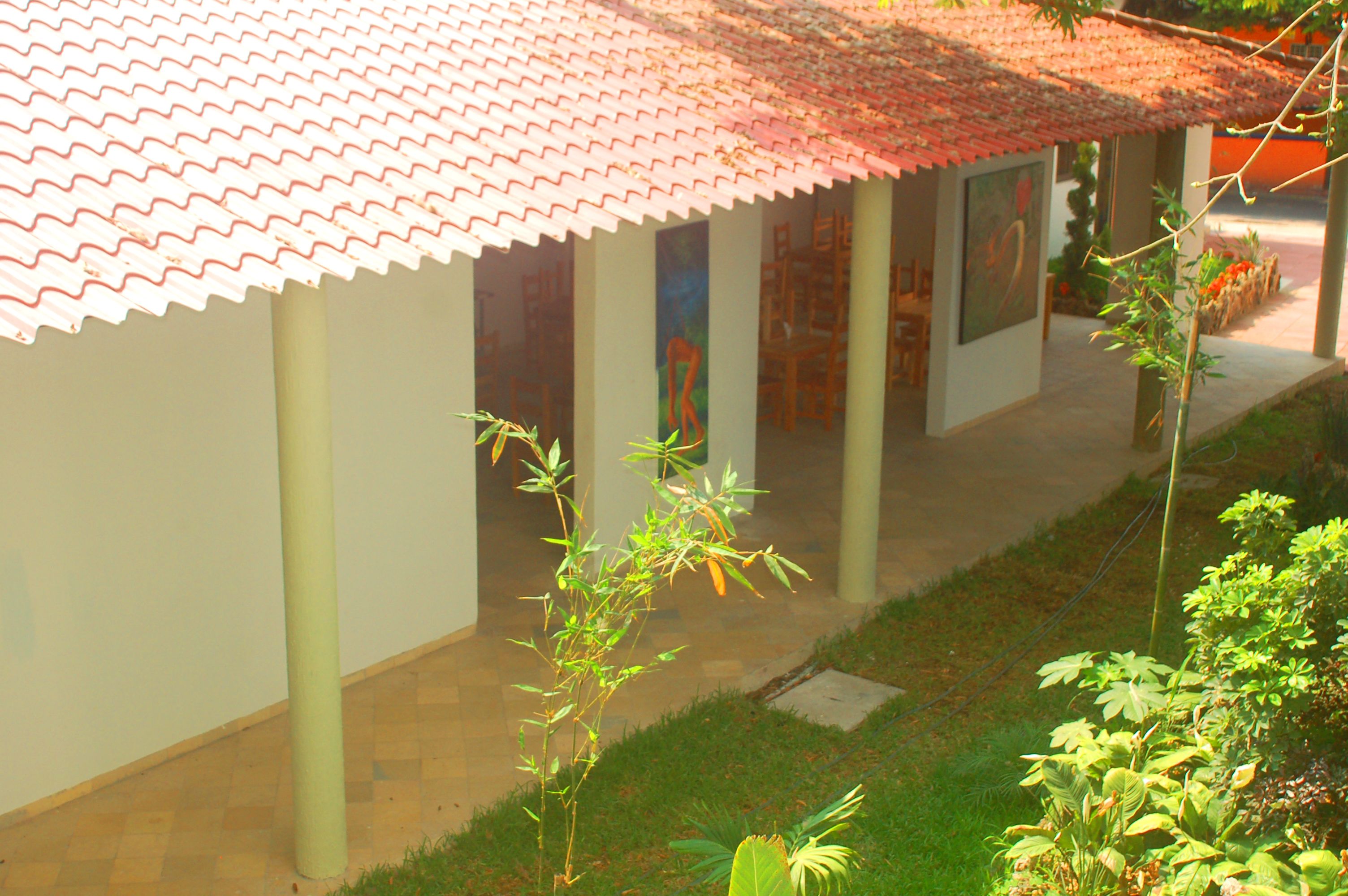 A building with a tiled roof, columns, and a pathway leading to an entrance.