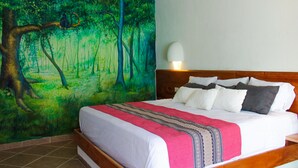 A bedroom with a large mural of a forest scene, a wooden headboard, and a bedside lamp. - Axkan Arte Hotel Tuxtla (Tuxtla Gutierrez)