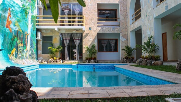 A modern building with a swimming pool, stone facade, and tropical mural. - Axkan Arte Hotel Tuxtla (Tuxtla Gutierrez)