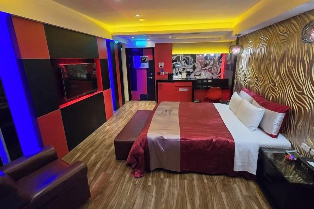 A modern hotel room with a large bed, a desk, and a seating area.