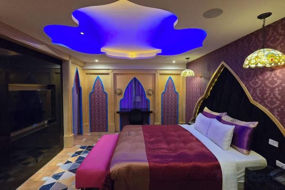Une chambre dotée d’un grand lit, d’une télévision et d’un décor de plafond original.
