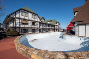Un edificio tradicional con piscina, paredes de piedra y un edificio rojo al fondo.