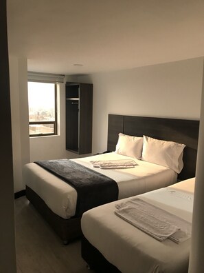 Ein Hotelzimmer mit zwei Betten, einem Kleiderschrank und einem Fenster mit Blick.