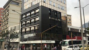 A multi-story building with a modern glass facade, a ground-level restaurant named 'Dolce Pecato', and a visible bus stop. - Hotel Express 53 (Bogotá)