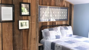 A bedroom with a wooden panel wall, a bed with a quilt, and framed pictures. - Riverboat Bed & Breakfast (Natchez)
