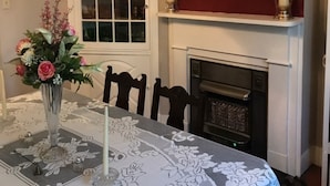 A dining room with a chandelier, a fireplace, and a painting on the wall. - Riverboat Bed & Breakfast (Natchez)