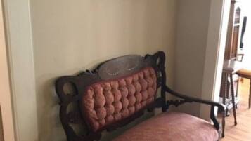 A corner with a wooden bench against a wall, a framed picture above it, and a wooden floor.