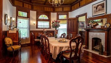 A dining room with a wooden table, chairs, stained glass windows, and a fireplace.