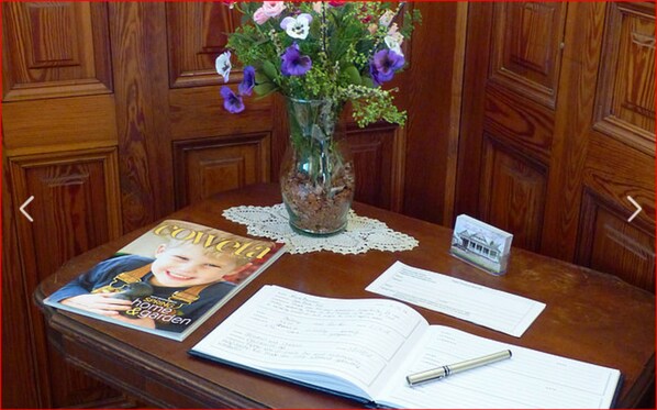 Una mesa de madera con una revista, un cuaderno abierto y un bolígrafo.