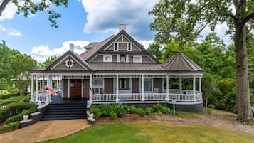 A large, two-story house with a wrap-around porch, a covered front porch, and a small gazebo.
