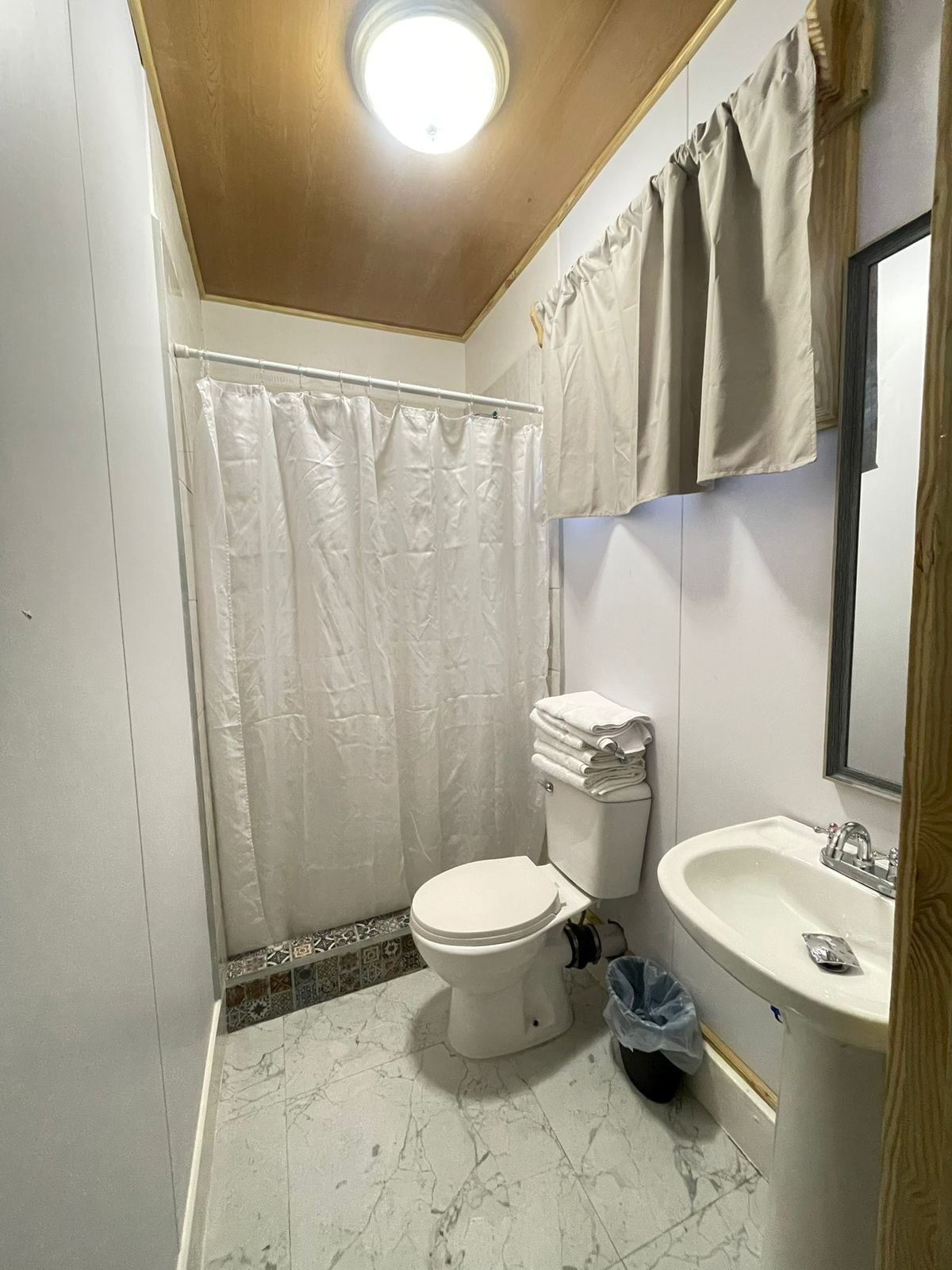 Un baño con inodoro, lavamanos y cortina de ducha.