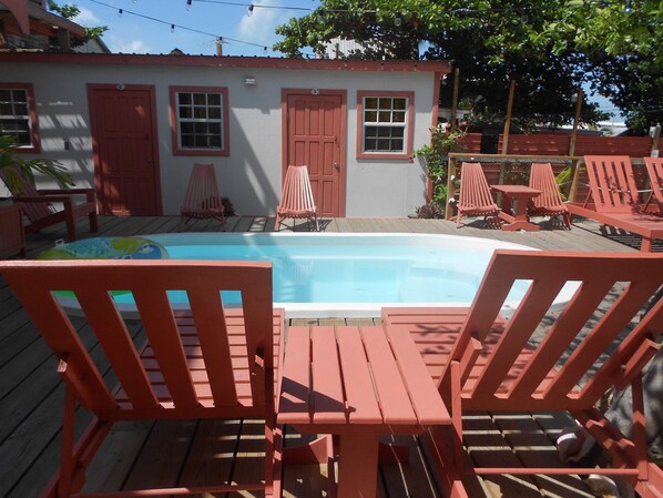 A pool area with wooden deck chairs and a pool. - Ambergris Sunset Hotel (San Pedro)