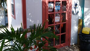 A small building with a red door and a sign that reads "OPEN". There is a sign on the wall that says "OFFICE". - Ambergris Sunset Hotel (San Pedro)