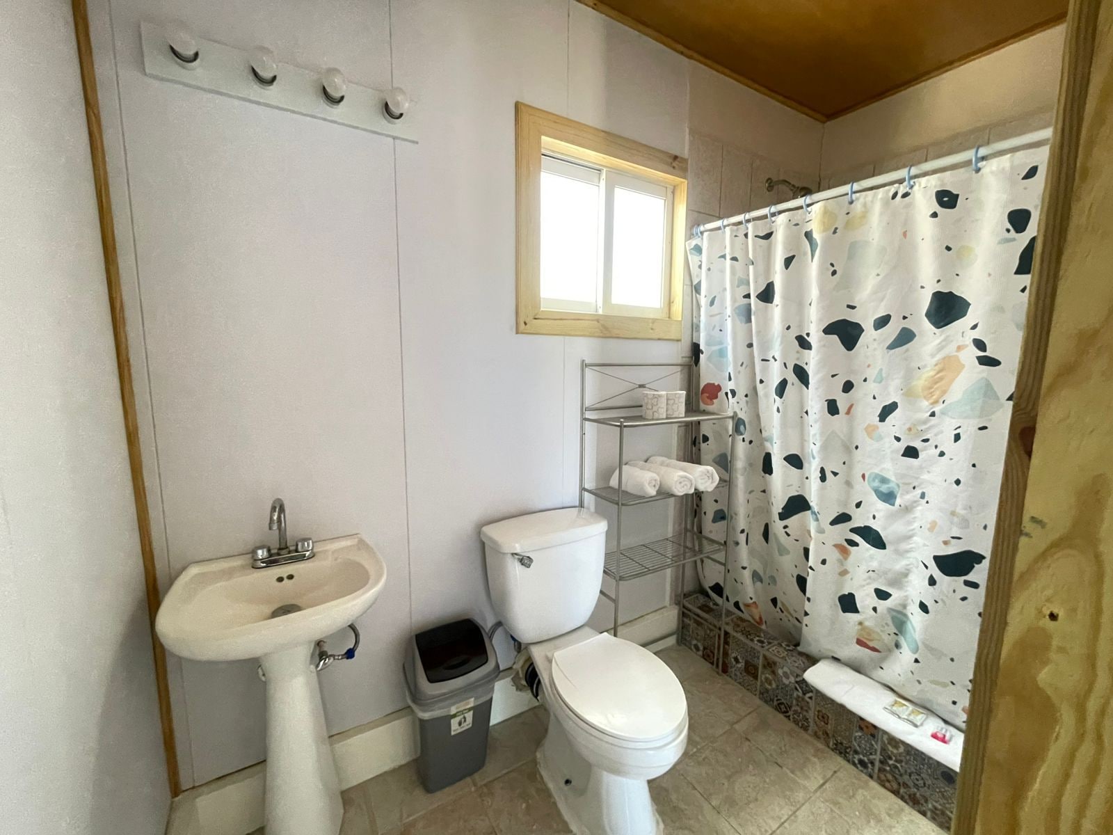 Une salle de bain avec un lavabo blanc, des toilettes et un rideau de douche à motifs pointillés.
