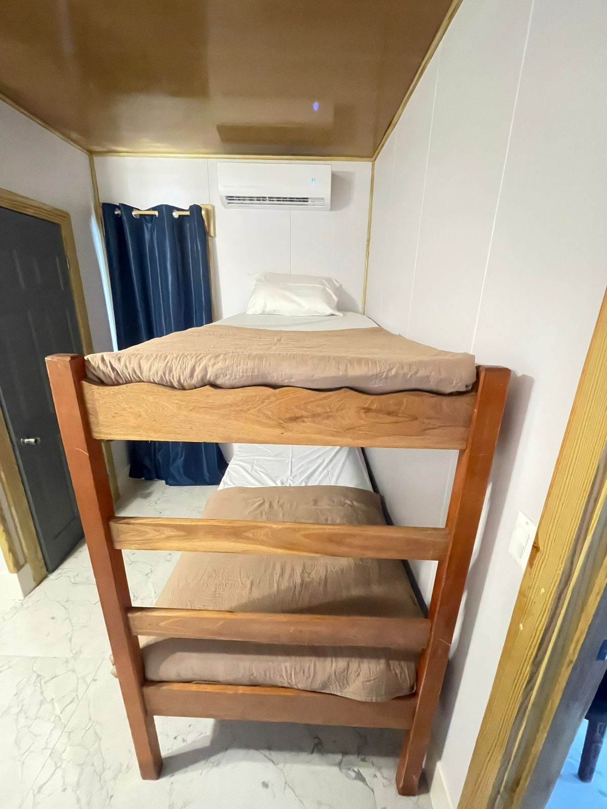 A bunk bed with a wooden frame and beige bedding.