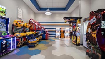 An indoor arcade with various gaming machines, a hexagonal patterned floor, and a sign that reads 'EAT SLEEP SURF'.
