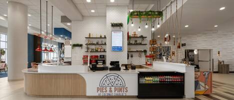 A modern counter with a logo, a menu board, and a beverage cooler.
