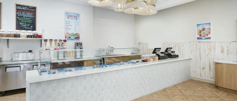 Una heladería limpia y moderna, con un mostrador que exhibe distintos sabores y acompañamientos de helado.