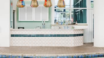 A bar area with a tiled countertop, a pool, and a sign above the bar.