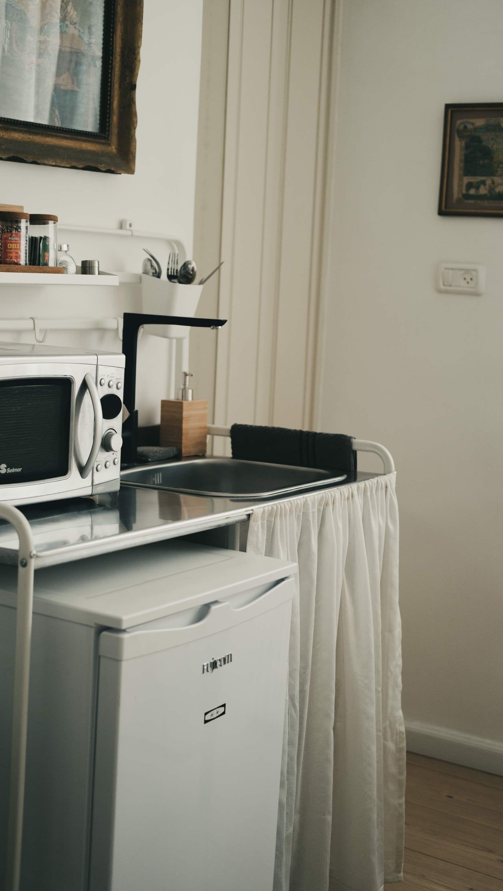 Een kitchenette met een magnetron, een kleine koelkast en een koffiezetapparaat.