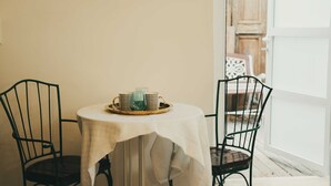 A round table with a white tablecloth, two black chairs, and a tray with a green glass and two metal mugs. - Tzefania Hotel (Jerusalem)