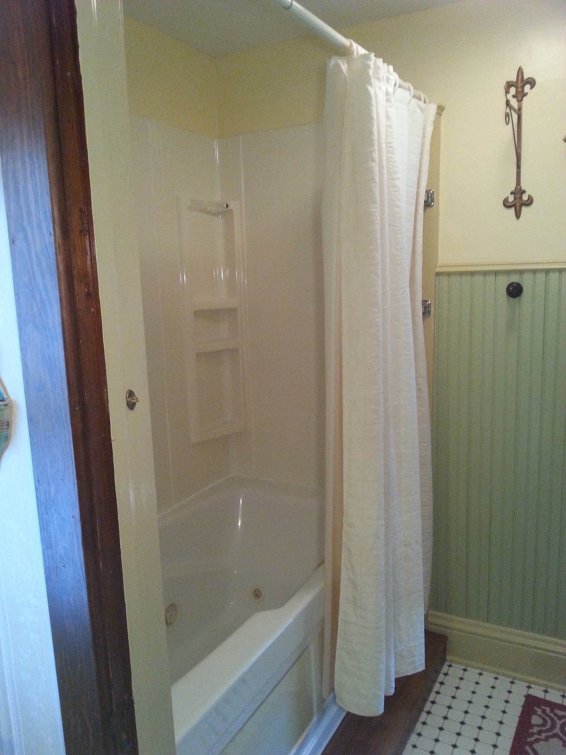 A bathroom with a bathtub, a shower curtain, and a wall-mounted towel rack.