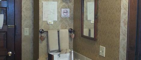 Un baño con tocador de madera, un lavabo y un espejo. Hay un letrero de 'No Fumar' en la pared.
