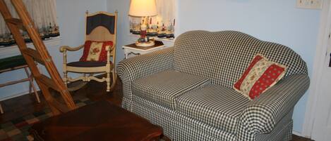 A cozy living room with a checkered sofa, a wooden chair, a wooden table, and a lamp.