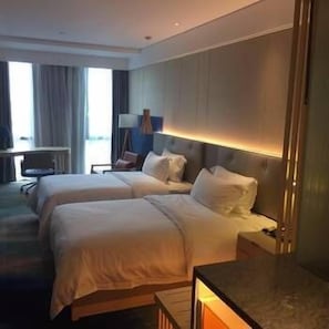 Une chambre d’hôtel avec deux lits, un bureau et une chaise.