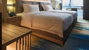 Een moderne hotelkamer met een groot bed, nachtkastjes, een bureau en uitzicht op de stad.