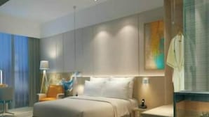 Een moderne hotelkamer met een groot bed, nachtkastjes, een bureau en een badkamer met douche.
