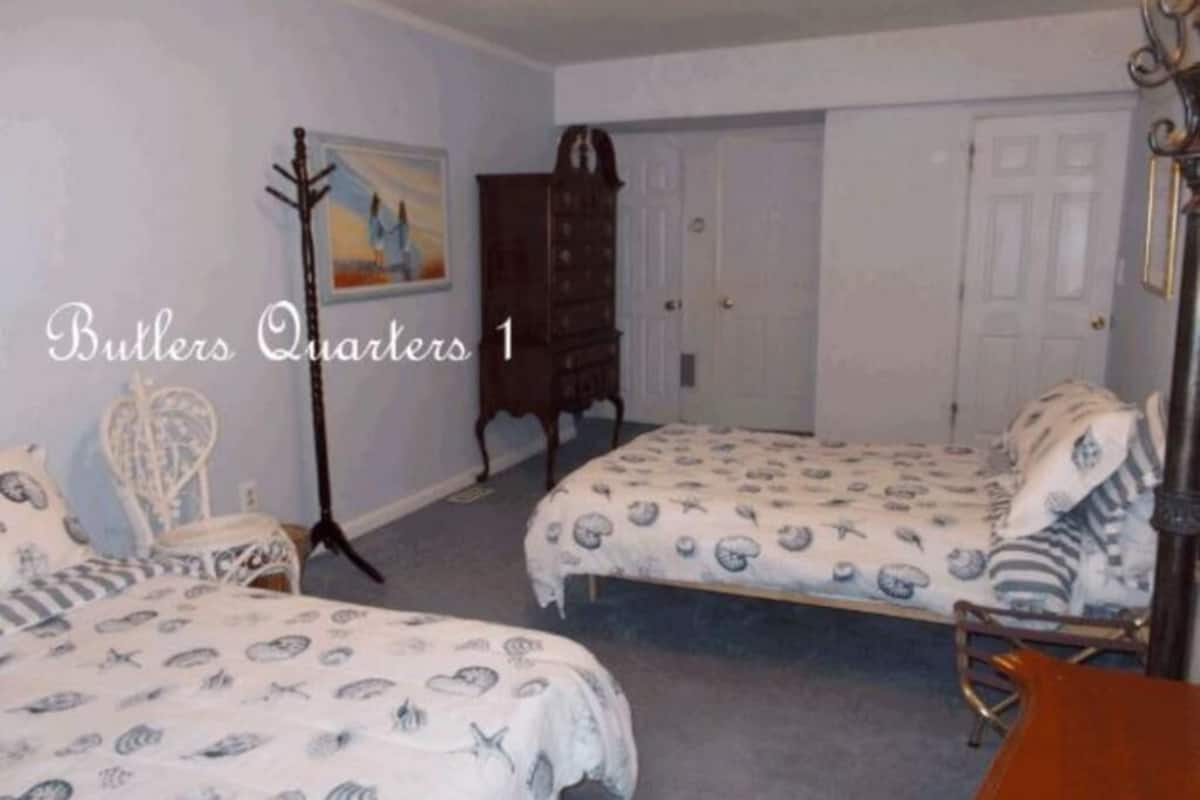 Une chambre avec deux lits, une chaise, un porte-manteau et une porte.