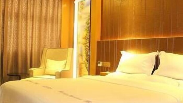 A hotel room with a large bed, a wooden headboard, a chair, and a window with curtains. - West Lake Hotel (Shenzhen)