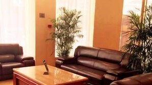 A living room with a leather sofa, a wooden coffee table, and two potted plants. - West Lake Hotel (Shenzhen)