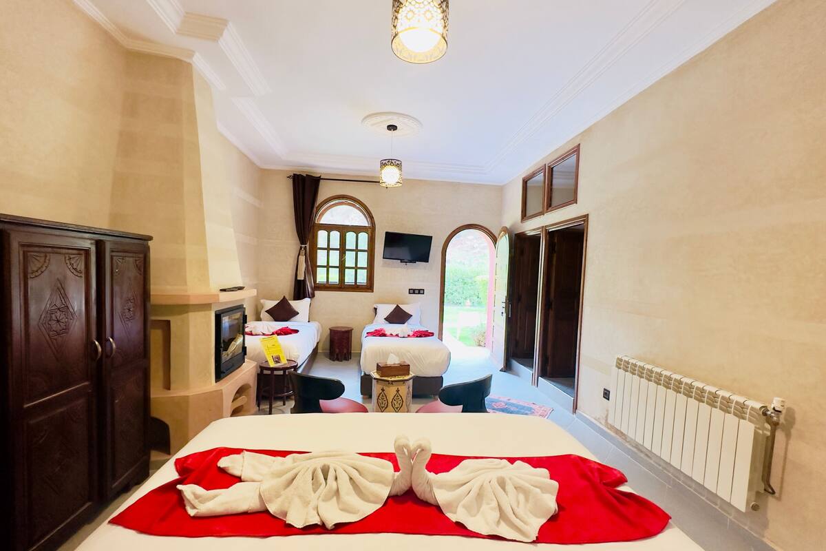 A hotel room with a large bed, two bedside tables, a TV, and a window with curtains.