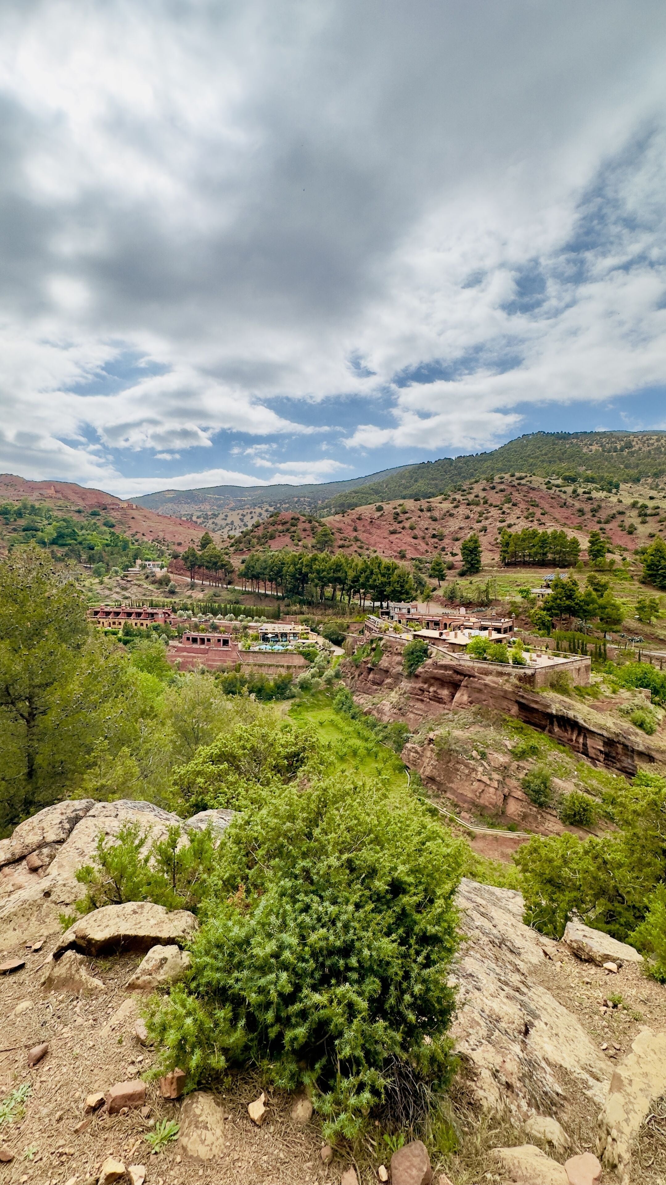 A mountainous landscape with a small settlement featuring traditional architecture, terraced fields, and a clear sky.