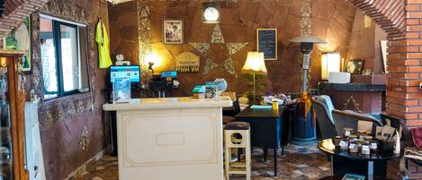 A reception area with a counter, a computer, a small stool, a table with brochures, and a fireplace.