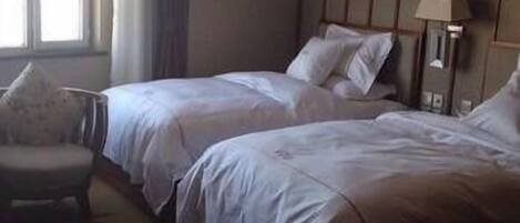 Ein Hotelzimmer mit zwei Betten, einem Sessel und einer Lampe.