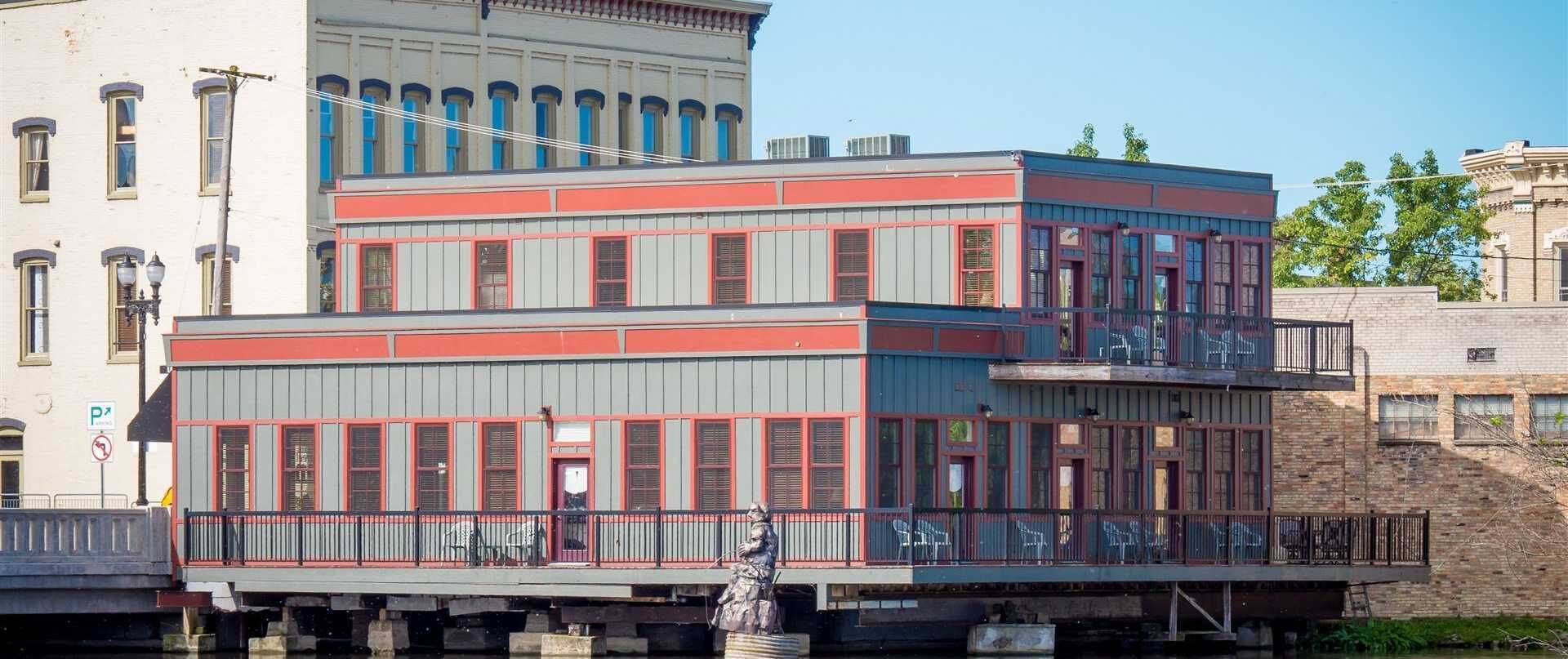 A multi-story building with a balcony and a statue in front.